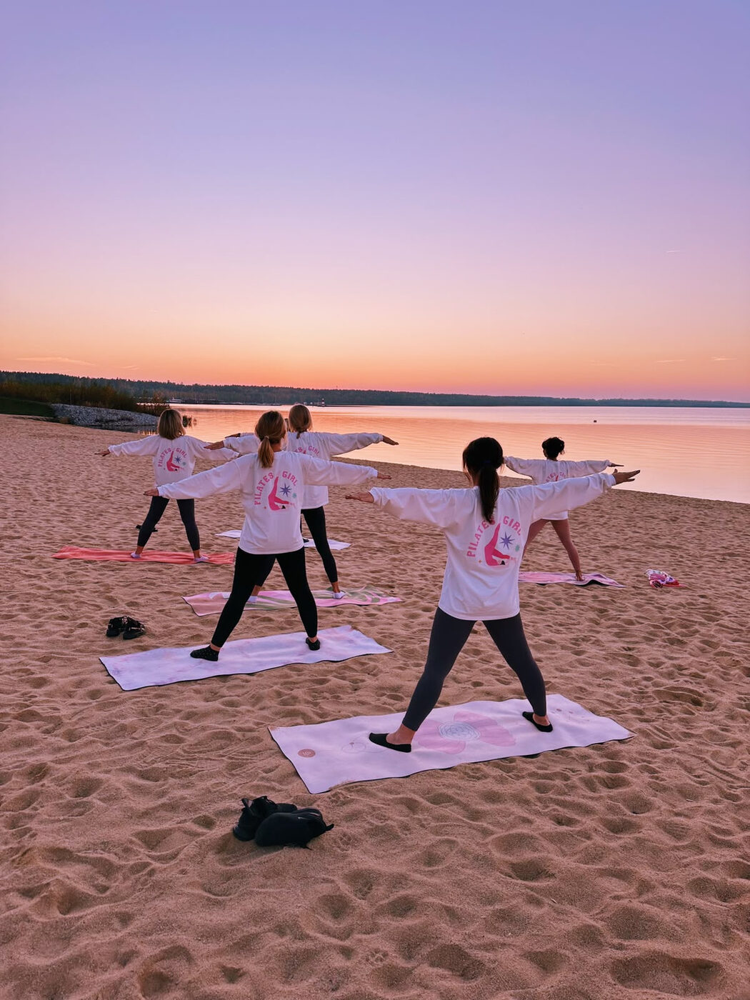 Grupa ćwicząca pilates na plaży o zachodzie słońca